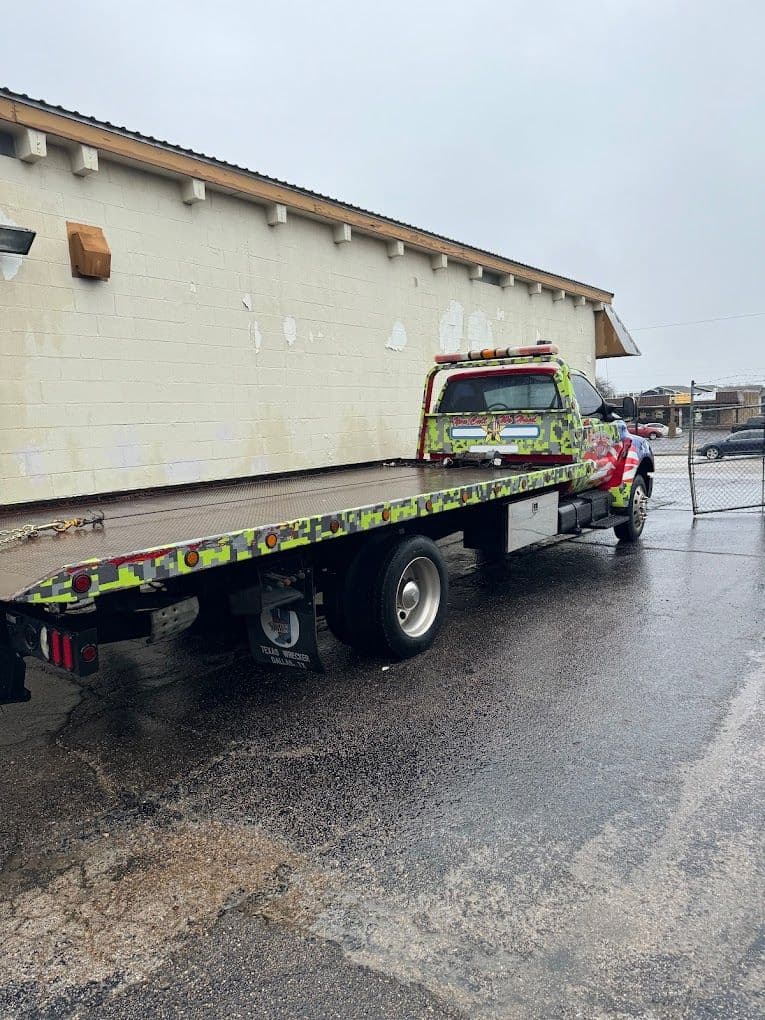 Colorful tow truck parked outside a building on a rainy day.